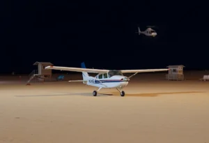 Small airplane safely landing on Huntington Beach at night.