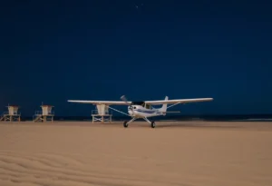 Small plane landing on sandy beach at night.